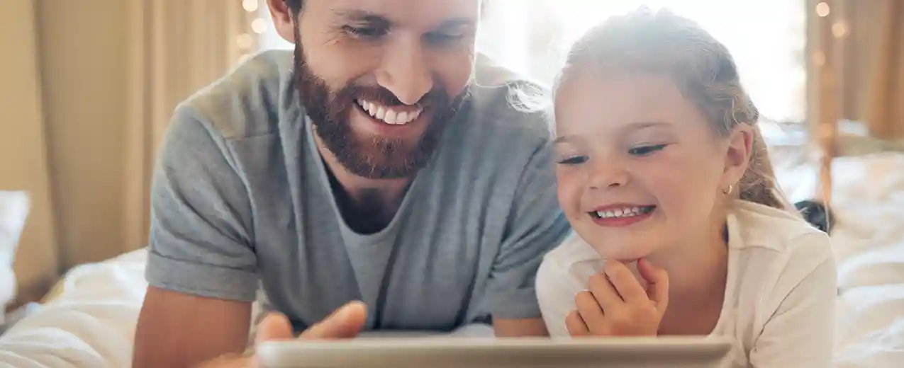 Dad and daughter looking at scanned negatives on a tablet