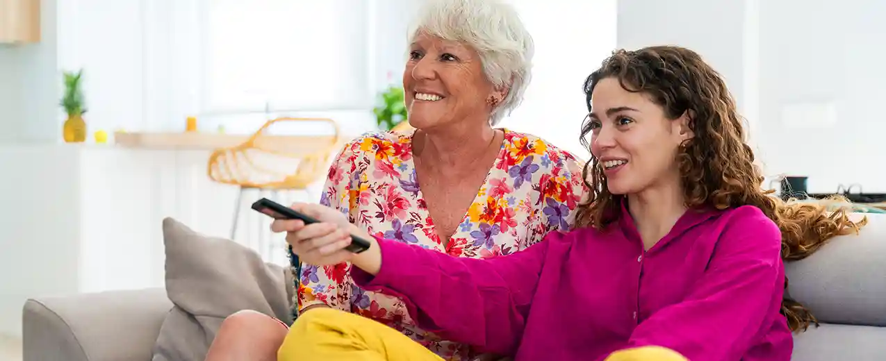 Mother and daughter using TV remote control